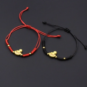 Detailed view of red and black woven bracelets with golden Yuanbao fortune pendants
