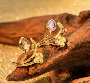 Macro detail of gold flower rings with lavender and champagne crystals on wood