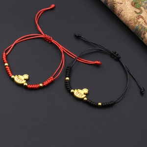 Detail of handmade braided bracelets with gold sycee charm in red and black colors