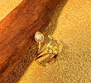 Detail of gold open ring with pear-cut stone and embossed flower on rustic wood