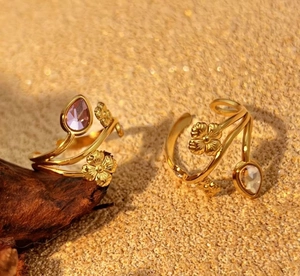 Detailed close-up of golden floral open ring with purple and clear teardrop gemstones