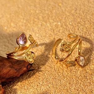 Bohemian gold plated rings with daisy flowers and teardrop crystal stones on sand background