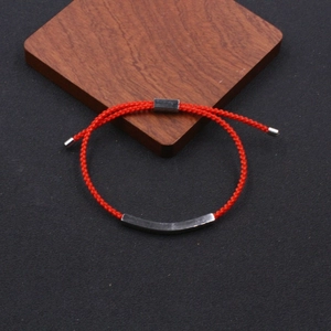Macro detail of red braided rope bracelet with curved stainless steel metal tube element