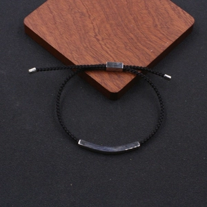 Detail of adjustable black braided cord bracelet with curved stainless steel metal tube