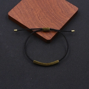 Detail view of adjustable black braided rope bracelet with matte gold stainless steel tube