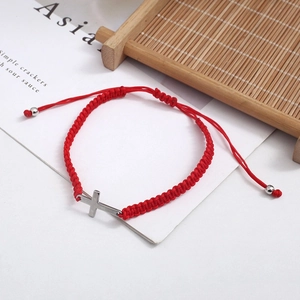 Close-up of red woven cord bracelet with silver metal cross and adjustable drawstring