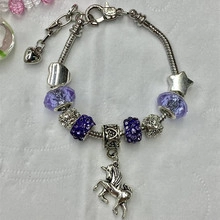 Close-up of silver-tone unicorn charm bracelet with purple and blue glass beads