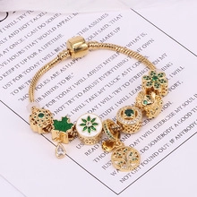 Close-up of gold-plated bracelet with Tree of Life and green enamel leaf charms