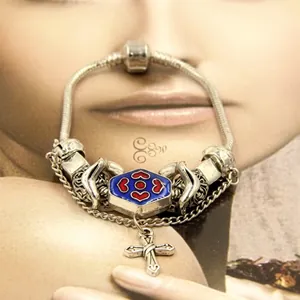 Detailed macro view of silver snake chain bracelet featuring blue enamel bead and cross charm