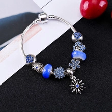Detailed macro view of silver snake chain bracelet with blue zircon beads and snowflake pendant
