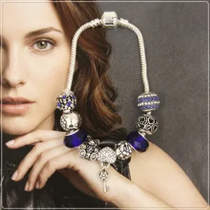 Detail view of silver charm bracelet featuring blue faceted beads and a heart lock pendant