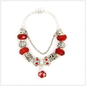 Detail of red faceted glass beads and silver leaf charms on a beaded charm bracelet