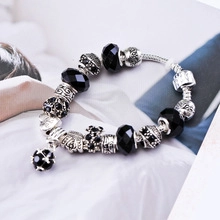 Detailed view of silver charm bracelet with black crystal beads and spherical pendant