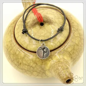 Close-up of a figure skating charm bracelet with black cord and red adjustment knots
