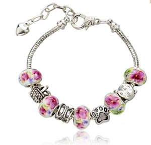 Close-up of silver snake chain bracelet with purple floral beads and clock charms