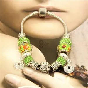 Vue macro d'un bracelet en argent avec perles pavées vertes et pendentifs cœur