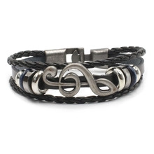 Detail of multi-layer braided leather bracelet featuring a silver treble clef music note