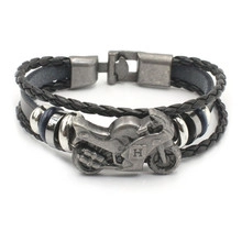 Close-up of vintage leather bracelet with motor bike charm and blue decorative rings