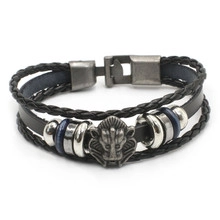 Detail of vintage layered black leather bracelet featuring an antique silver lion head charm