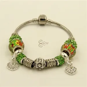 Détail macro du bracelet à breloques argenté avec perles en cristal vert et cœurs