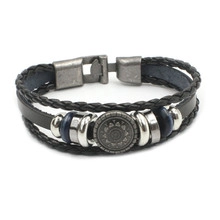 Detail view of multi-layer black leather bracelet with sunburst metal charm and silver clasp