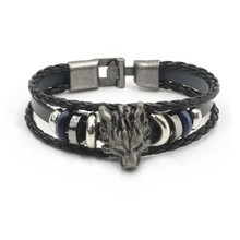 Close-up of a punk leather bracelet featuring a silver wolf head and braided black bands