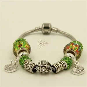 Vue macro d'un bracelet maille serpent avec perles pavées vertes et breloques cœur
