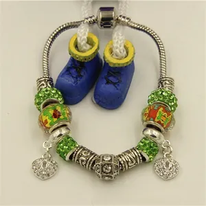 Détail d'un bracelet maille serpent argenté avec perles en cristal vert et breloques cœur