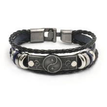 Macro detail of men's leather bracelet showing woven texture and Tai Chi yin yang metal plate