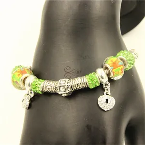 Détail du bracelet avec perles de cristal vert et pendentif clé en forme de cœur