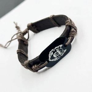 Detailed close-up of a woven leather bracelet featuring a white wolf head totem design