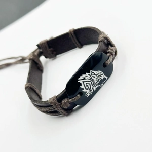 Close-up of vintage brown leather bracelet with wolf head moon totem and woven cotton rope
