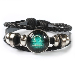 Macro shot of multilayer leather bracelet with glowing Libra zodiac glass dome charm