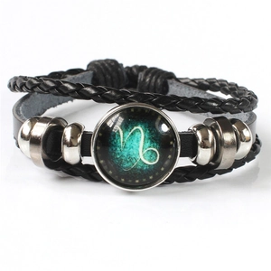 Close-up of multilayer leather bracelet featuring green Capricorn zodiac symbol in glass