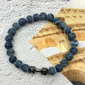 Beaded natural stone fitness bracelet with dark grey dumbbell charm on textured background