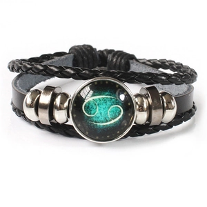 Detail of multi-layer leather bracelet featuring glowing Cancer zodiac sign and glass dome