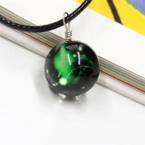 Macro shot of galaxy glass ball necklace with green nebula effect and black wax cord