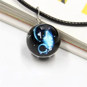 Detail of galaxy glass ball necklace with blue nebula pattern and silver wire wrapping