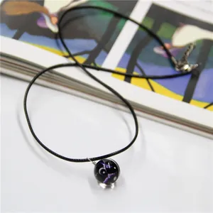 Close-up of galaxy star sphere pendant with deep purple nebula texture on black cord