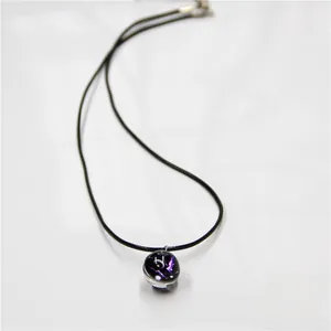 Macro view of zodiac necklace with deep blue glass sphere pendant on black wax cord