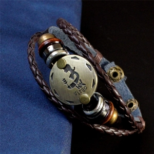 Détail du charm Vierge en bronze sur bracelet multicouche en cuir tressé marron