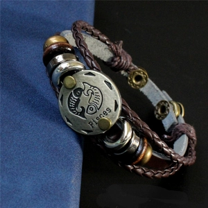 Détail du bracelet multicouche en cuir avec breloque zodiaque Poissons et cordons tressés