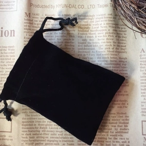 Eleganter schwarzer Samtbeutel mit Kordelzug für Schmuck auf Vintage-Papier