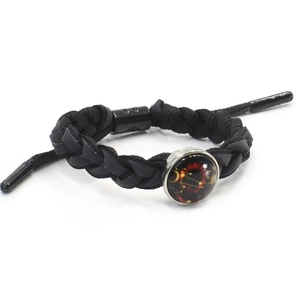 Detail of hand-woven black cord bracelet with round zodiac glass pendant and metal ring