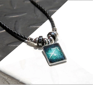 Gros plan du pendentif Sagittaire avec motif de nébuleuse bleue et perles noires