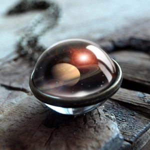 Macro shot of solar system Saturn double-sided glass ball pendant on rustic wood background