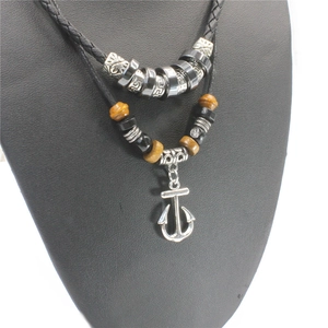 Detail van de dubbellaagse ankerketting met zilveren patronen en bruine houten kralen