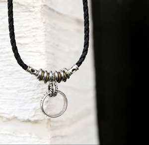Macro-opname van gegraveerde metalen ringhanger met retro kralen aan zwart gevlochten koord