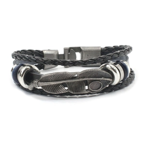 Macro view of multi-layer leather bracelet featuring vintage metal feather pendant