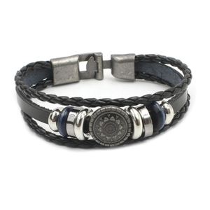 Detail van de meerlaagse vintage leren armband met metalen kralen en een zon totem badge
